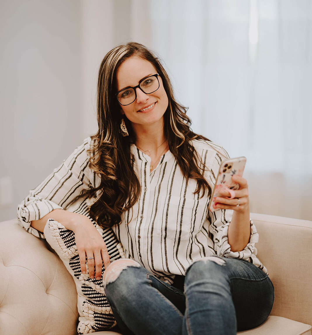 woman holding phone sitting on couch